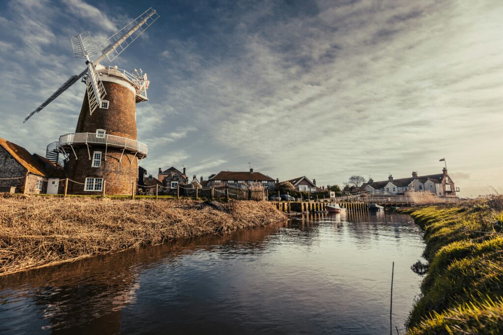 Photo of Cley Windmill in Holt with river alongside and houses in the background