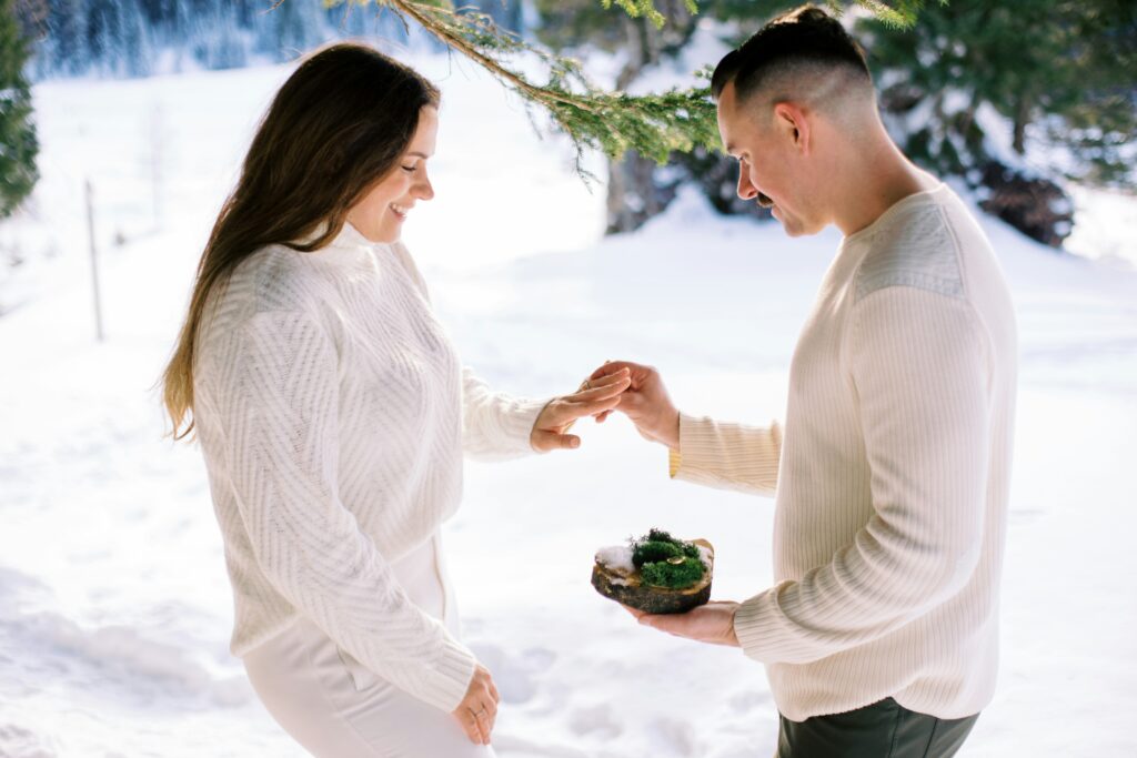 Female and male couple with engagement rings with snowy landscape in the background