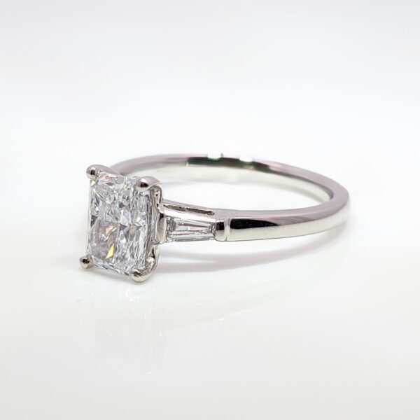 This Platinum Emerald Cut Lab-Grown Diamond Ring with Tapered Shoulders has a 1.10cts centre stone with D Colour and VS1 Clarity.